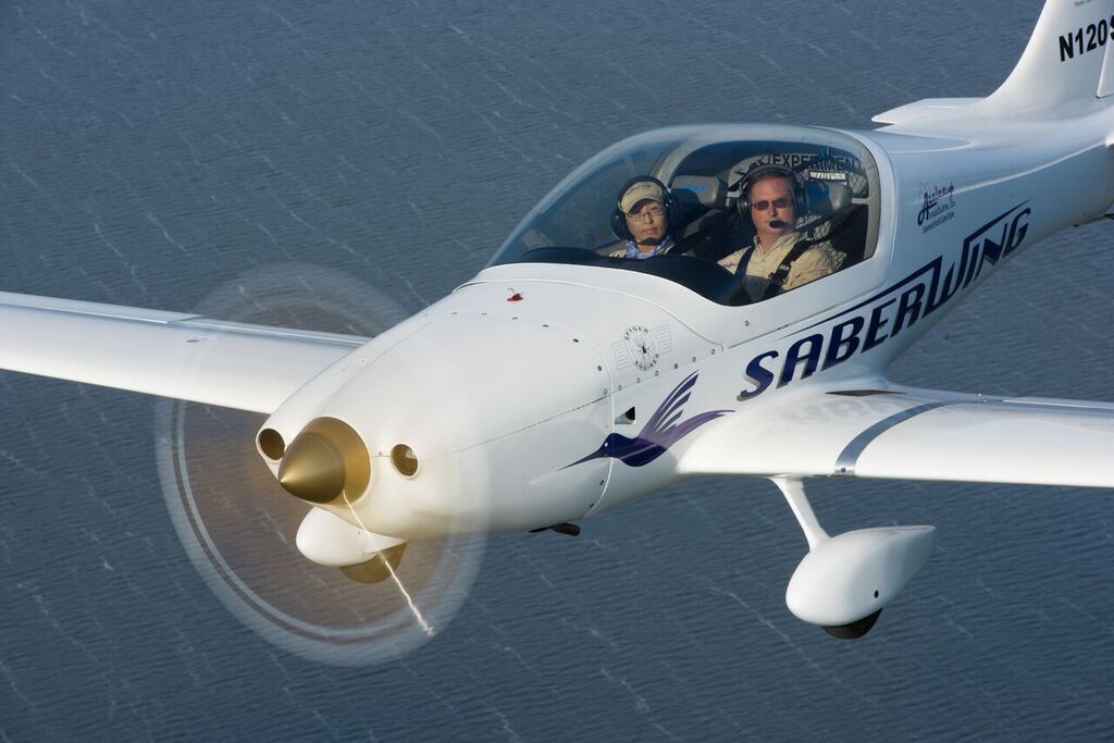 Bill and Kyoung Clapp flying a corvair powered Saberwing over water.